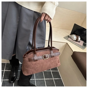 Detailed close-up of brown suede shoulder bag with leather straps and gold buckle detail