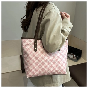 Detail of pink plaid tote bag with brown leather handles and golden rivets on shoulder