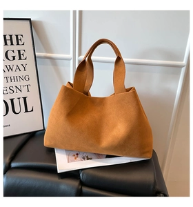 Caramel faux suede tote bag displayed on a sleek black bench with a minimalist background