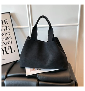Minimalist black tote bag with suede texture shown in a modern interior setting