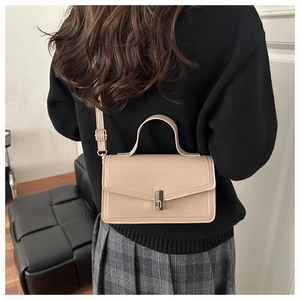 Detail of a beige vintage crossbody bag showing the flap closure and metal lock on a model