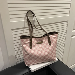 Pink checkered tote bag with brown leather straps and gold metal studs on a white surface