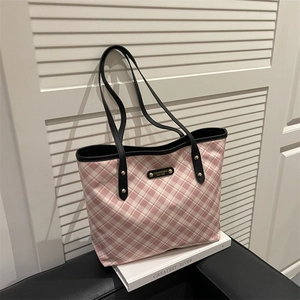 Pink and white checkered tote bag with black handles and gold rivet details on white books