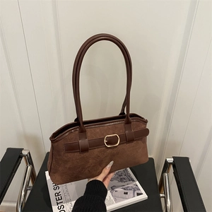 Vintage brown suede shoulder bag with leather straps and gold buckle detail on a chair