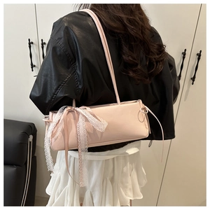 Detail of light pink shoulder bag with large white lace bow on matte faux leather