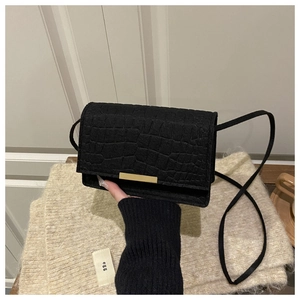 Détail d'un sac à bandoulière noir à motif crocodile avec boucle en métal doré