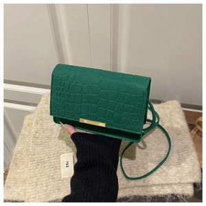 Détail du sac à main vert à motif crocodile avec fermeture à barre dorée élégante
