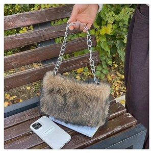 Sac à bandoulière en fausse fourrure avec chaîne argentée sur un banc avec des accessoires