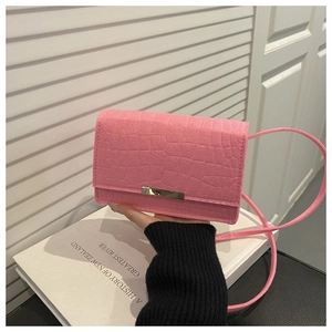 Détail de la texture crocodile rose et de la boucle en métal doré sur le petit sac