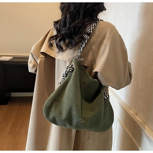 Dettaglio della borsa tote in velluto a coste verde scuro con tracolla intrecciata geometrica