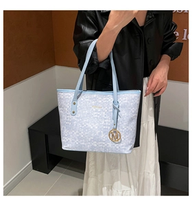 Gros plan d'un sac cabas bleu clair a carreaux avec logo dore et breloque en forme de M
