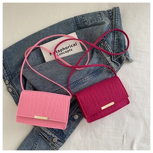 Détail de mini sacs bandoulière en similicuir crocodile rose et magenta sur du denim