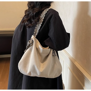 Dettaglio della borsa hobo in velluto a coste bianco crema con tracolla a righe