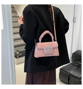 Detail of pink crossbody bag showing the rhinestone buckle and pleated handle texture