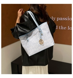 Dettaglio della borsa tote intrecciata azzurra con ciondolo M dorato e marchio ZIMEIBAG