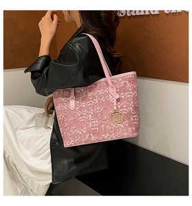 Dettaglio della borsa tote intrecciata rosa con ciondolo M e spalline sottili sulla modella