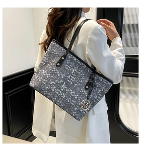 Close-up of a large grey textured tote bag with black straps on a white suit model