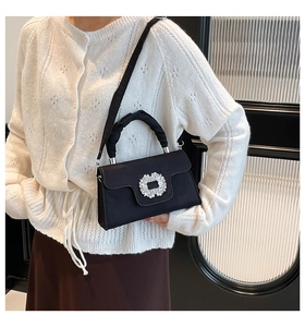 Detail of black satin pleated handbag with sparkling rhinestone buckle for women