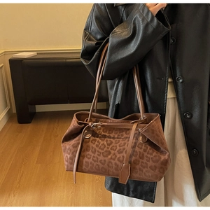 Close-up of leopard print tote bag with buckle detail and suede texture on model
