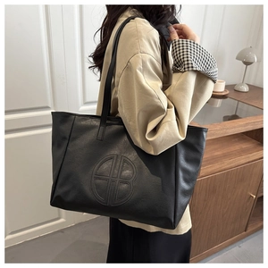 Chic black PU leather tote bag styled with a beige trench coat for a modern urban look
