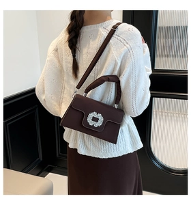 Detail showing the elegant rhinestone buckle and ruched handle of a brown crossbody bag