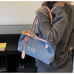 Detail of blue leopard print tote bag with pink leather straps and silver metal buckles