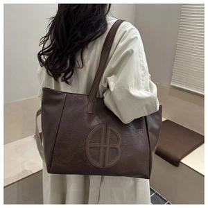 Detail of vintage brown leather tote bag with lychee texture and circular hollow logo