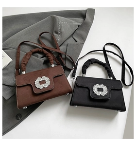 Close-up of matte suede handbags with sparkling rhinestone buckles in brown and black