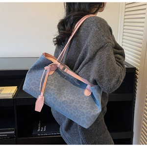 Detail of grey-blue leopard print tote bag with pink leather strap and soft suede texture
