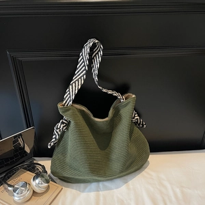 Borsa tote in velluto a coste verde scuro con tracolla a righe in ambiente moderno