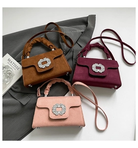 Close-up of three diamond-buckle velvet handbags in brown, wine red and light pink
