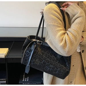 Detail of black faux leather tote with leopard embossing and decorative hangtag pendant