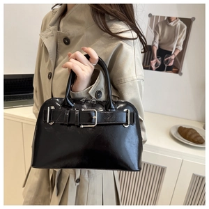Close-up of black patent leather handbag with silver buckle detail in a lifestyle setting