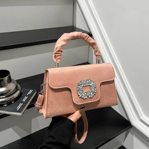 Pink textured crossbody bag with ruched handle and crystal buckle on stairs