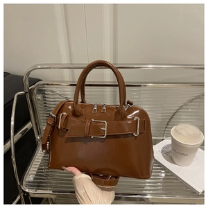 Detail view of brown glossy PU leather Boston bag with decorative buckle and silver zipper