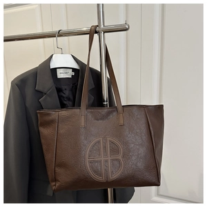 Detail of vintage brown leather tote bag with large HB embossed logo and spacious interior