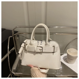 Detail of white glossy PU leather handbag featuring decorative buckle and top handle