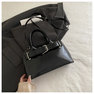 Close-up of black glossy PU leather handbag featuring metal buckle and adjustable strap