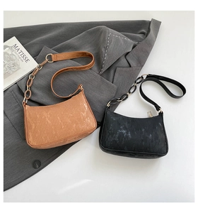 Detail view of black and brown textured baguette bags with gold chain shoulder straps