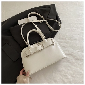 Detail of cream white PU leather handbag with decorative strap and silver hardware