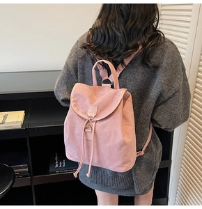 Pink matte backpack with drawstring closure and metal buckle detail shown on model