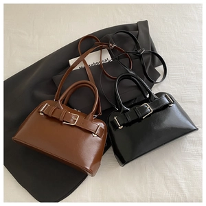 Close-up of brown and black PU leather handbags featuring metallic buckle decorations
