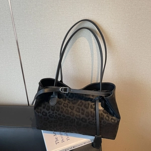 Large black leopard print shoulder bag with metallic buckle detail in a minimalist setting