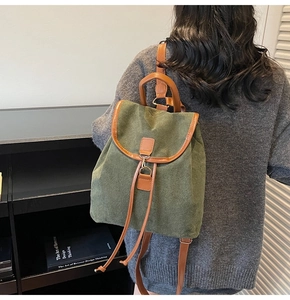 Detail of dark green canvas backpack with brown leather straps and metal buckle closure