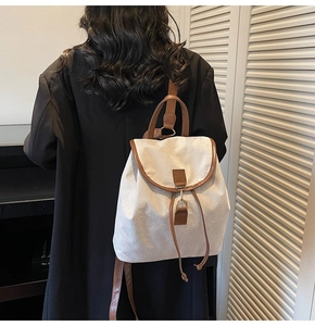 Close-up of the beige canvas backpack with brown leather flap and drawstring detail
