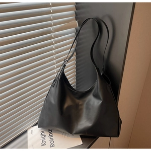 Close-up of black leather hobo bag showing matte texture and adjustable buckled strap