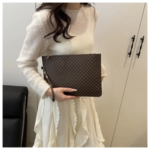 Close-up of a brown geometric pattern envelope clutch bag with metal zipper and wrist strap