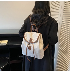 Detail view of retro cream canvas backpack with brown leather trim and metal buckles