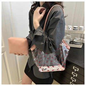 Detail of transparent cherry print tote bag and pink pouch set worn by a model