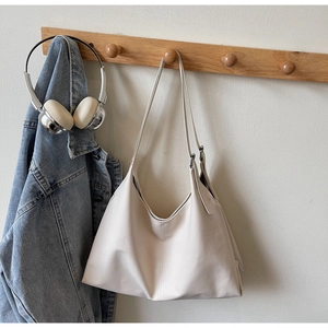 Detail view of adjustable leather strap and stitching on beige minimalist tote bag